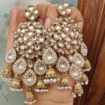 Beautiful Kundan and White pearl earrings are made of alloy and have gold colour plated on them, which are presented and held in the hands.